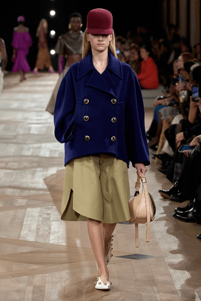 image41 Image may contain Bella Thorne Clothing Coat Accessories Bag Handbag Adult Person Overcoat Purse and Baseball Cap