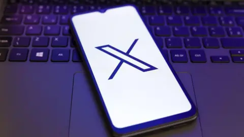 Getty Images X logo displayed on a smartphone lying on a laptop keyboard