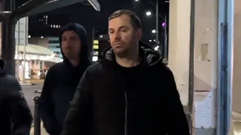 Roland Reka, on the left, and Florjan Reka - walk past a bus stop in Manchester.